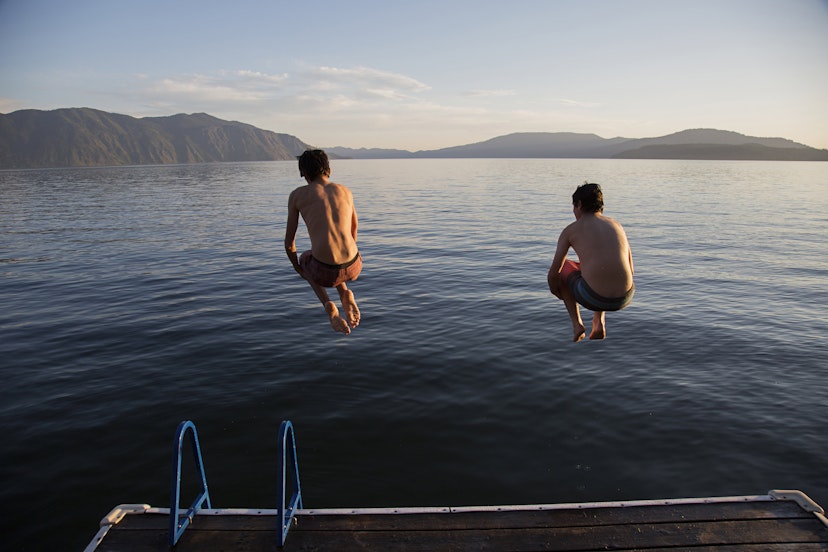 Boys jumping into lake from dock
