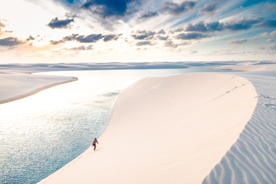 Young man climbing the sand dunes of Lençois Maranhenses.