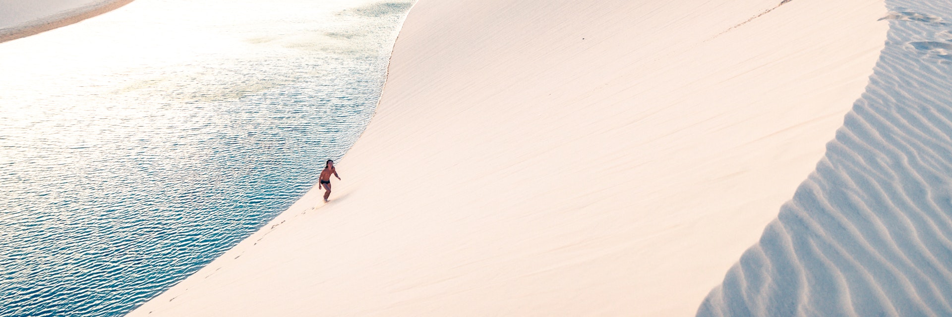 Young man climbing the sand dunes of Lençois Maranhenses.
