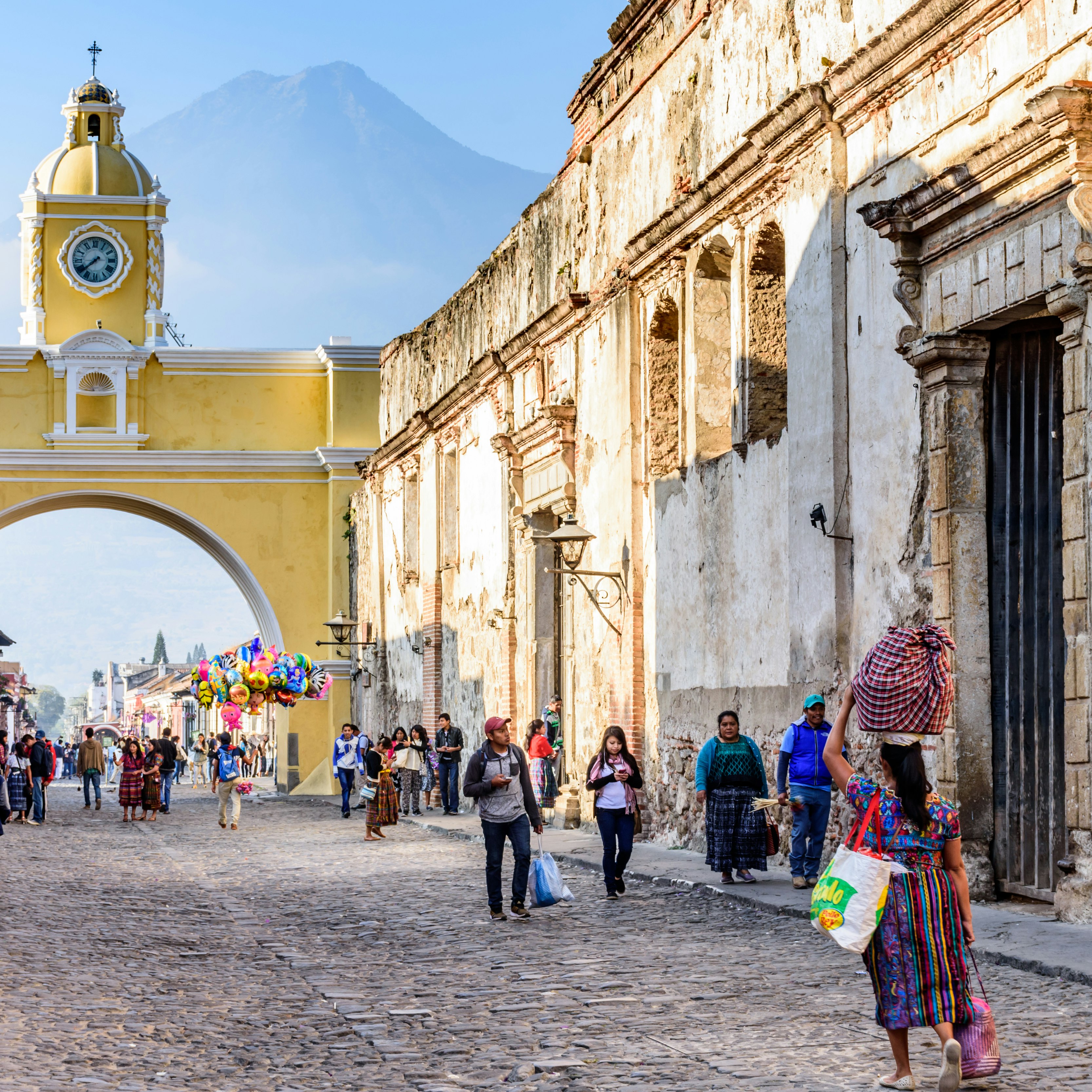 Locals and tourists walk by the Santa Catalina arch in Antigua, Guatemala