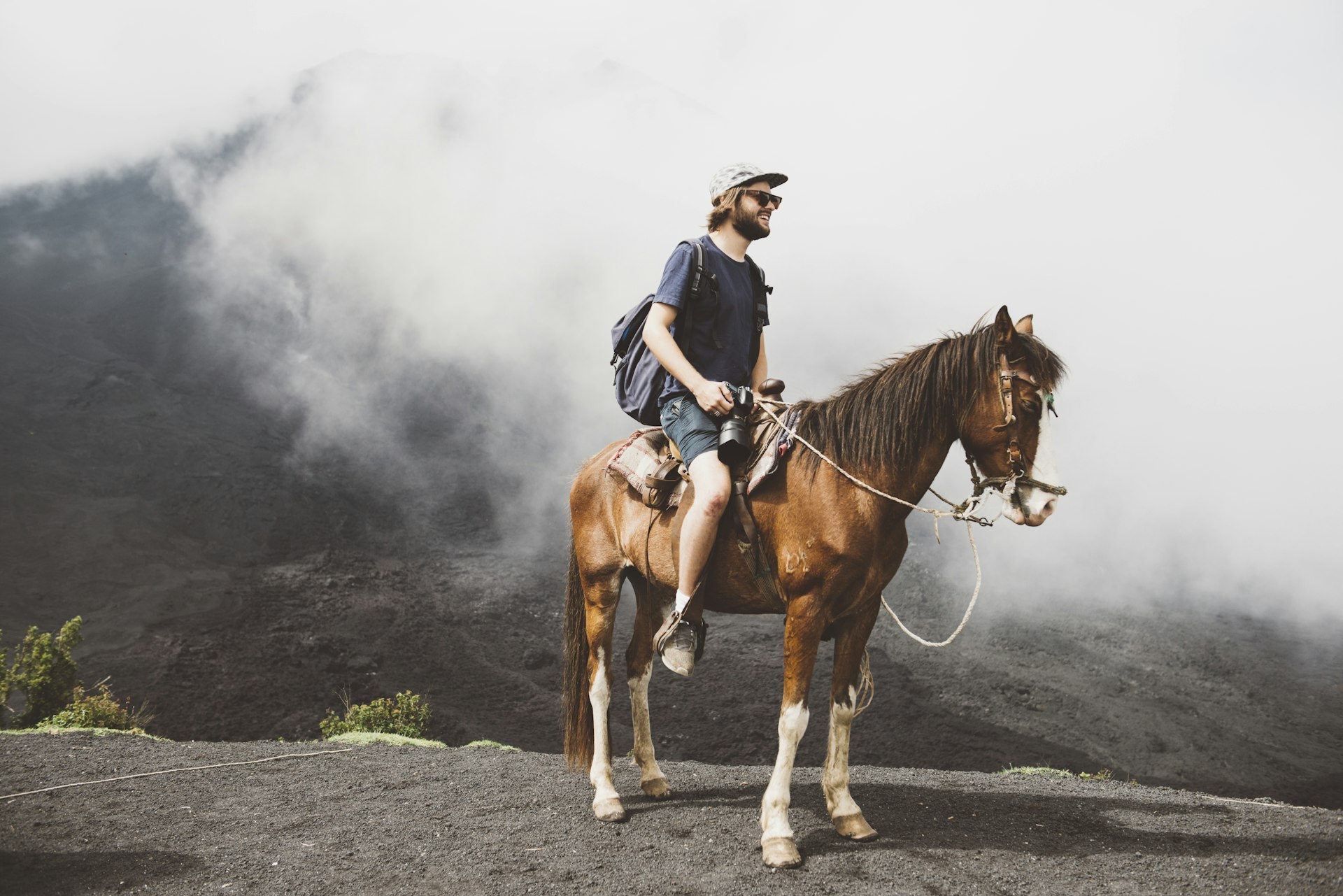 Young man on horseback trekking up Pacaya volcano, Antigua, Guatemala