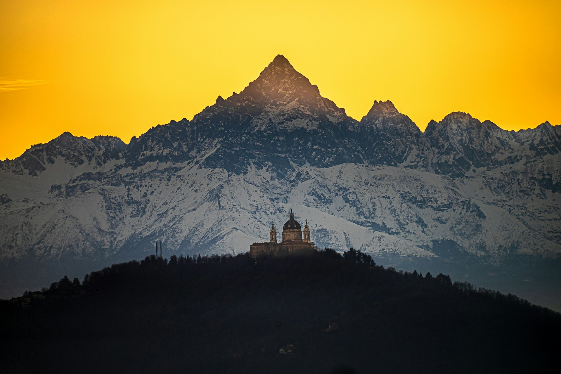 landscape photo of the Basilica of Superga with the Monviso mountains in the background at sunset, casting a wonderful hue of yellow