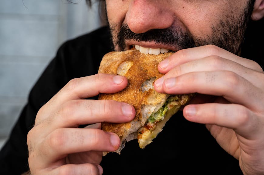 Un hombre barbudo come un sándwich tostado en Turín, Italia