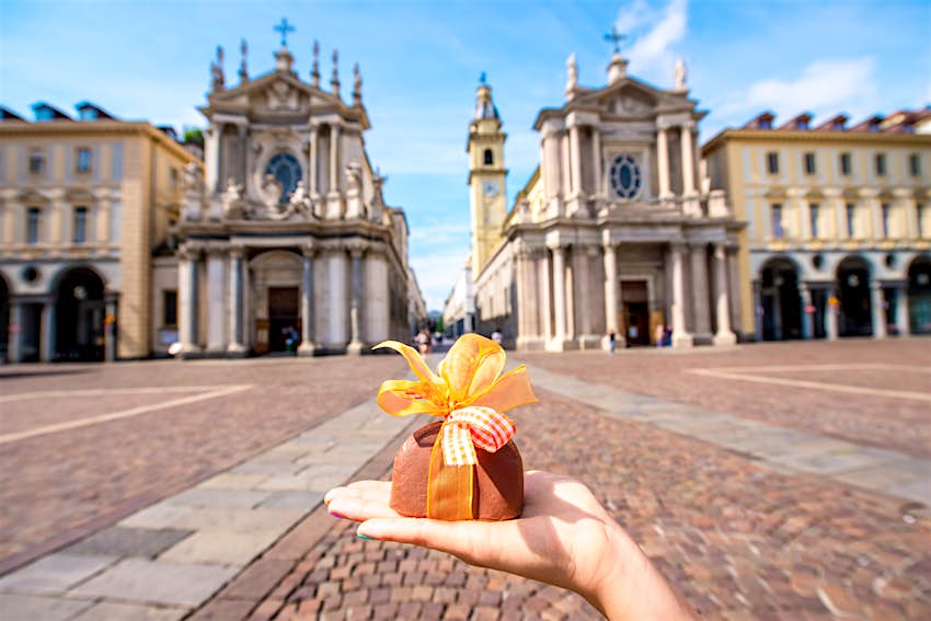 A hand holds up a wrapped piece of chocolate in a square in Turin, Italy