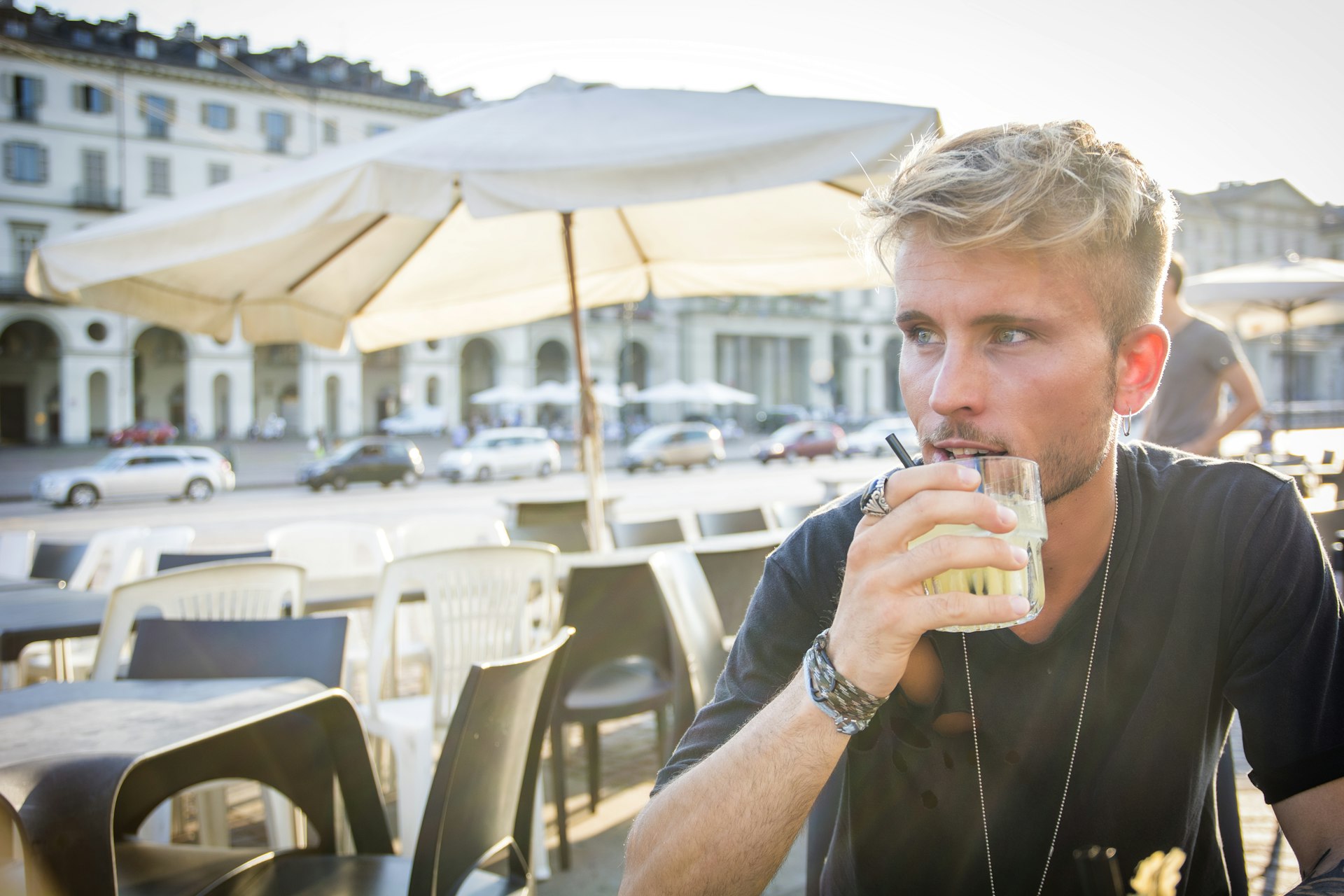 A blond-haired man drinks an aperitif outside a bar in Tuin