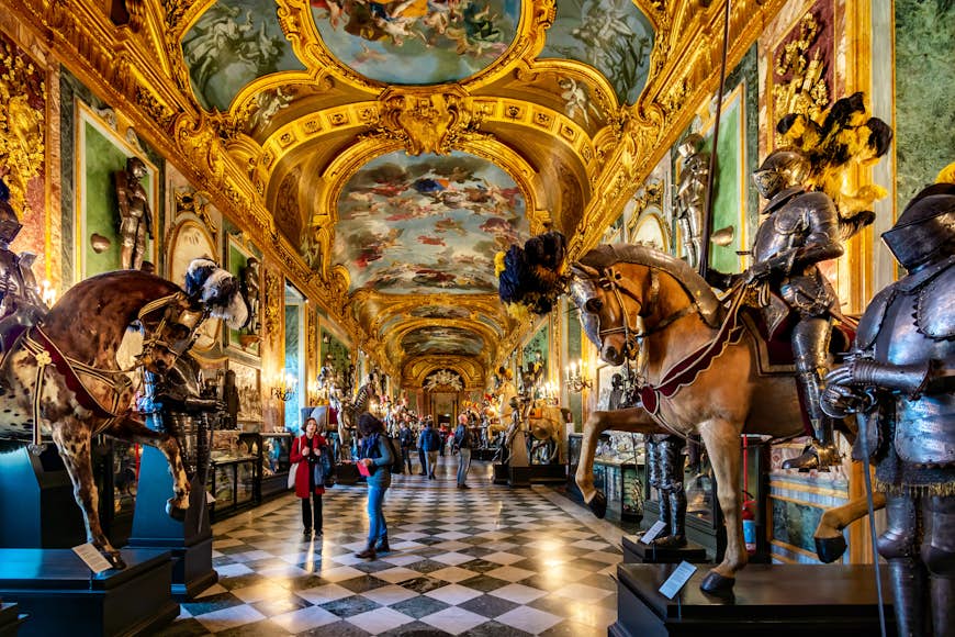 Una lujosa habitación en el Palacio Real de Turín decorada con obras de arte, armaduras y mucho pan de oro en el techo y las paredes.