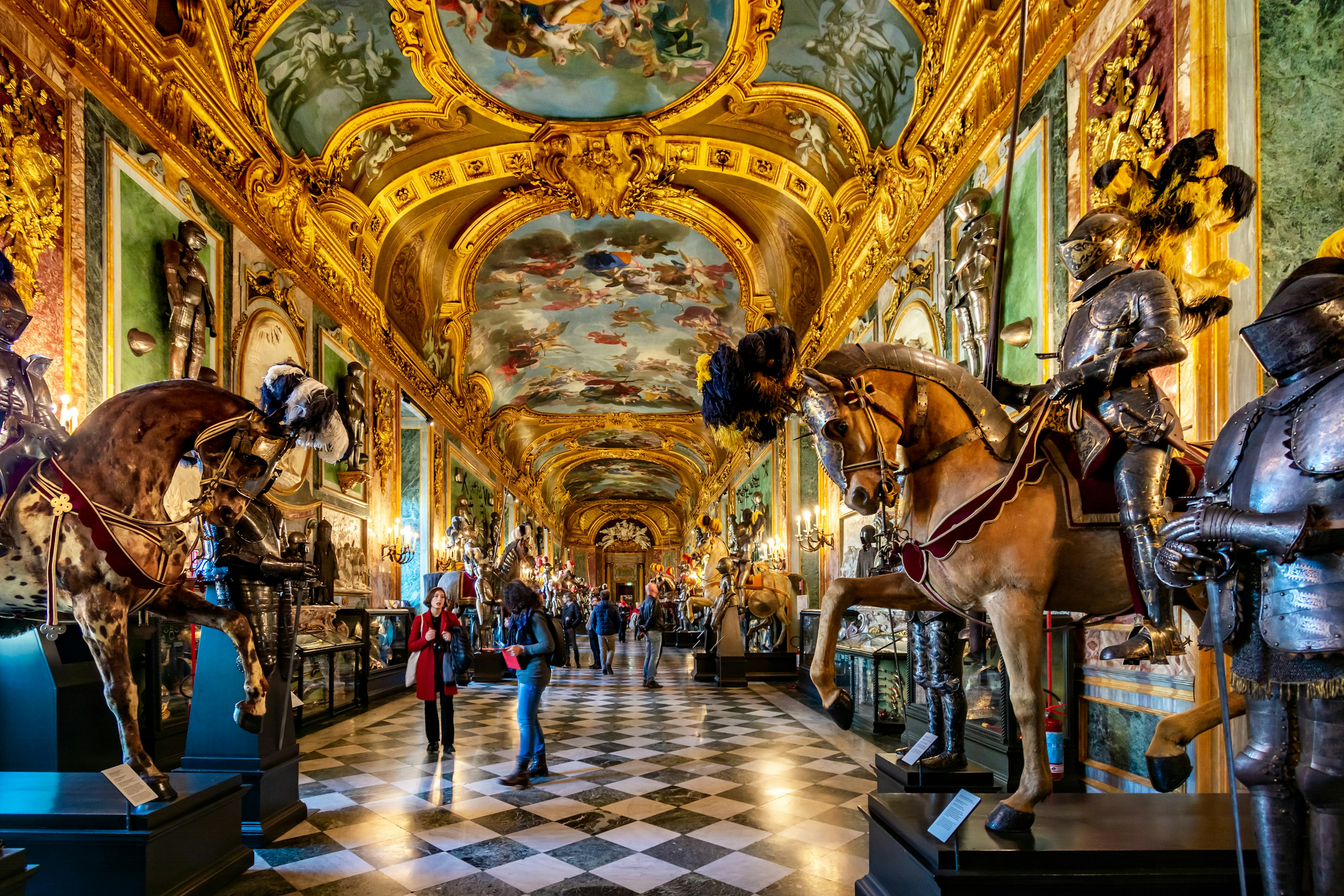 A lavish room in Turin's Royal Palace decorated with artworks, armour, and a lot of gold-leaf on the ceiling and walls