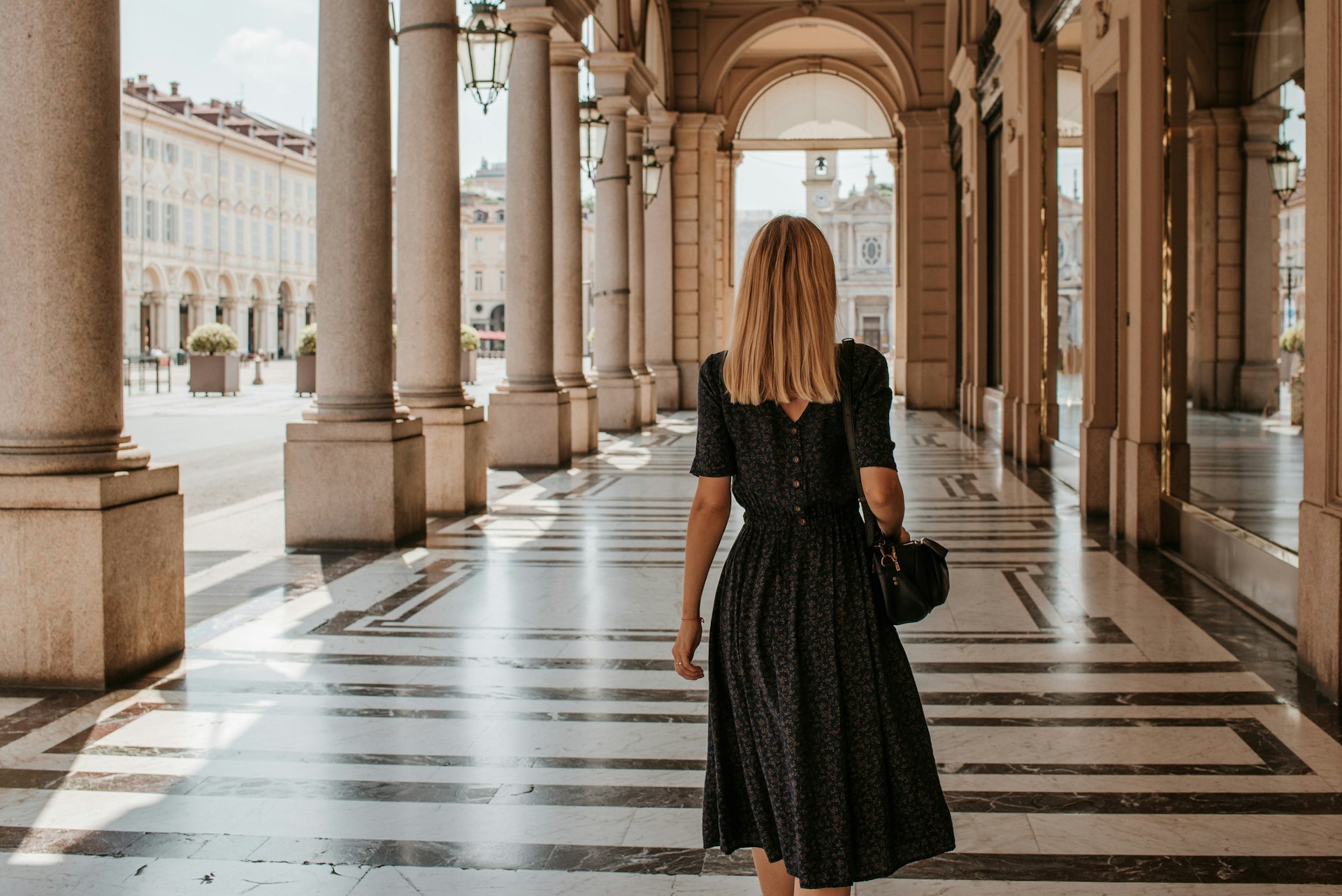 A woman walking along a sheltered portico in Turin, Italy