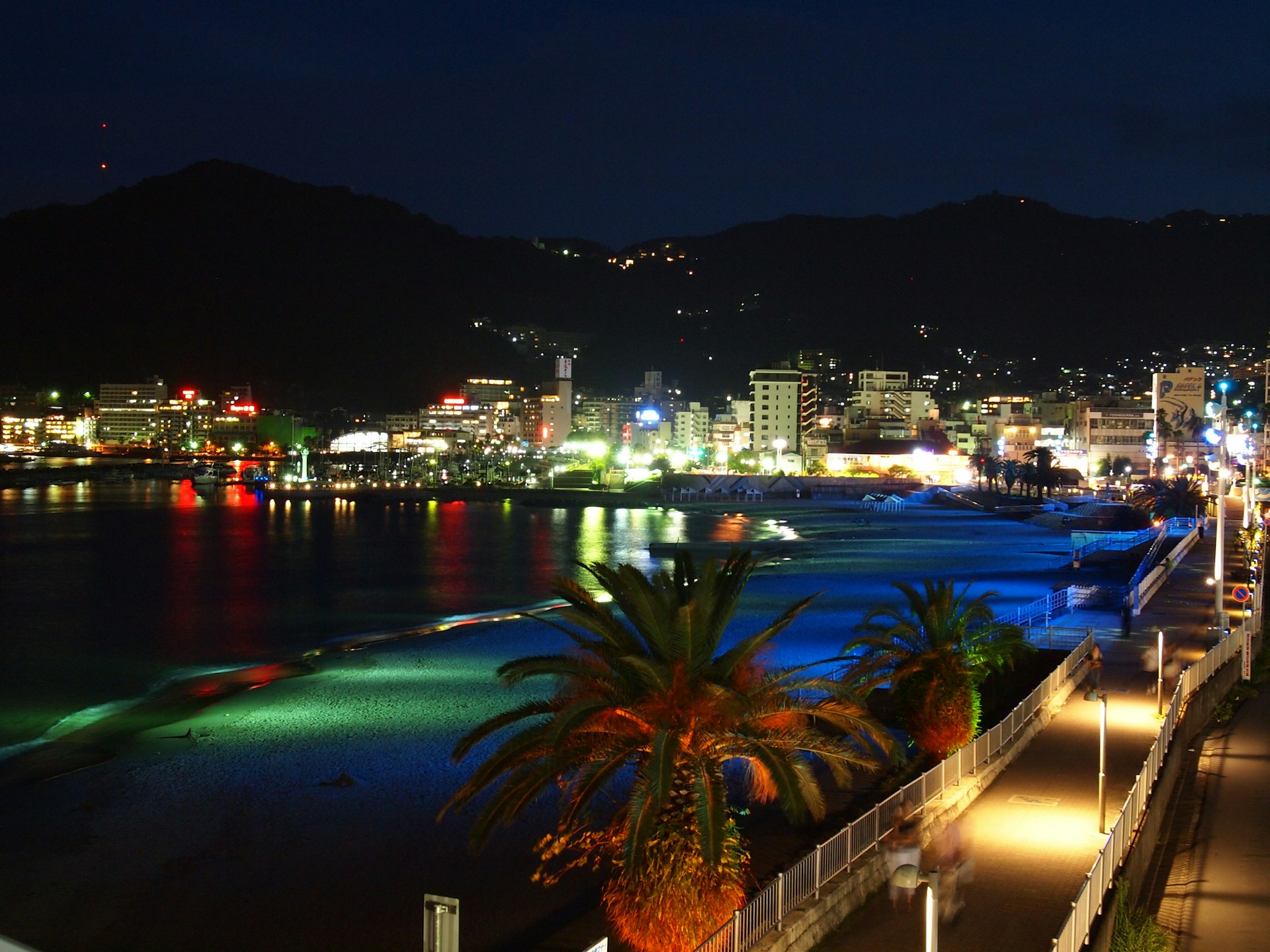 A beach at nighttime lit up by colorful lights