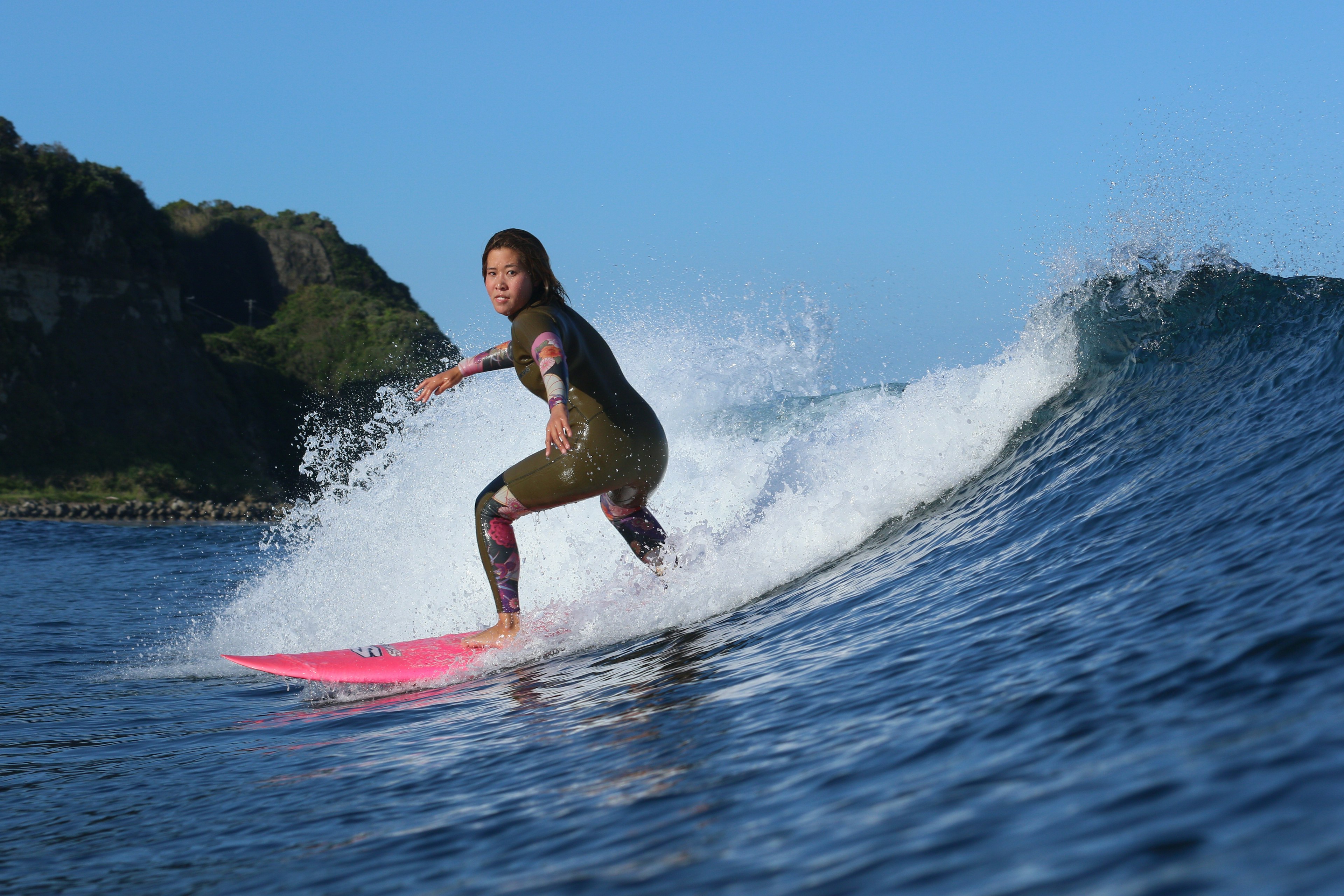 A Japanese female surfer, wearing a full wet suit, rides the waves in Chiba, Japan