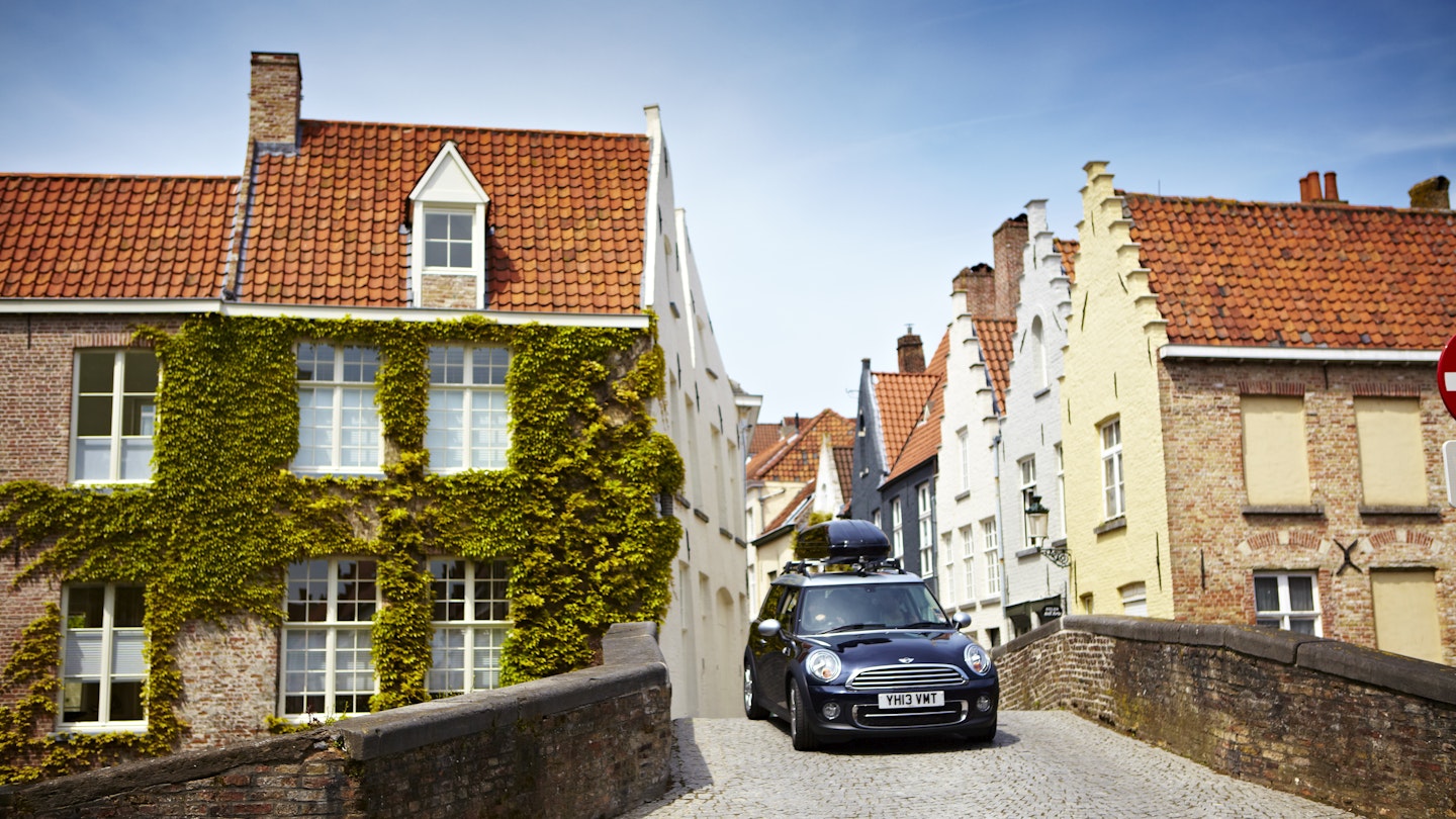 Mini driving on narrow cobbled street.