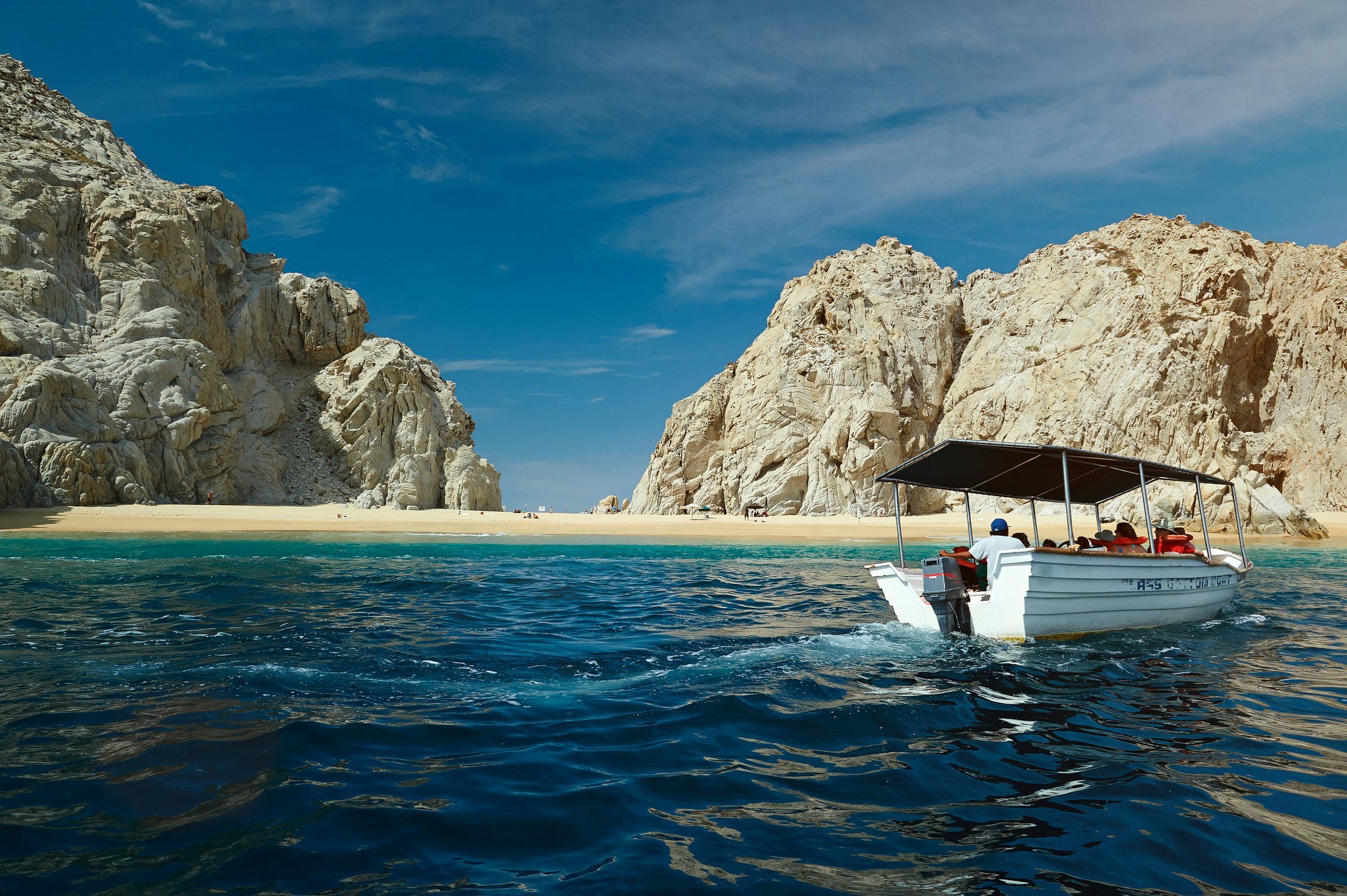 A water taxi with several passengers approaches a lovely golden sand beach