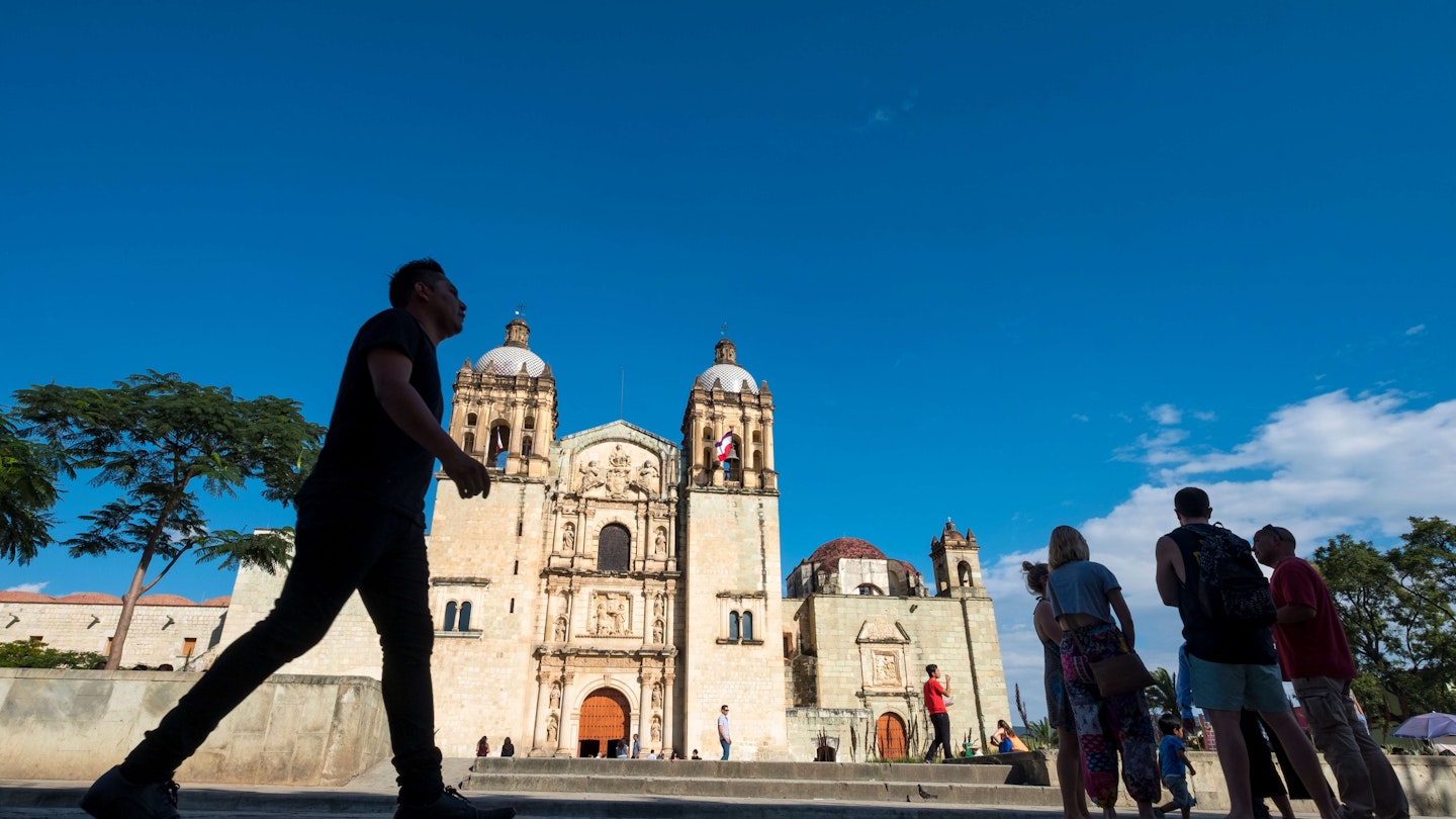People in silhouette in front of the Templo de Santo Domingo de Guzmán, in Oaxaca, Mexico