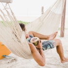 Man enjoying coconut water in hammock on beach
