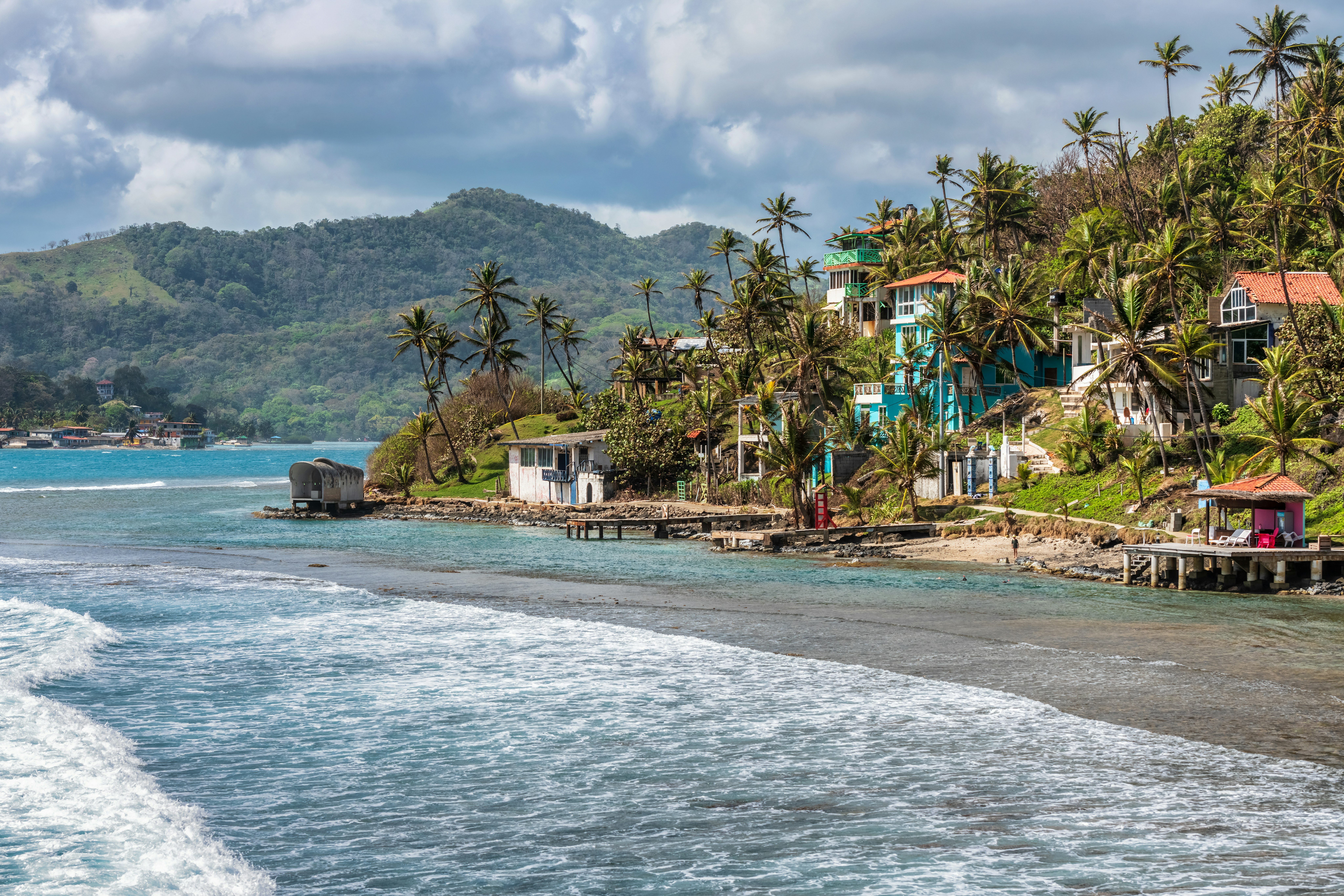 Palm trees, sea and houses on the shore of Isla Grande, Panama