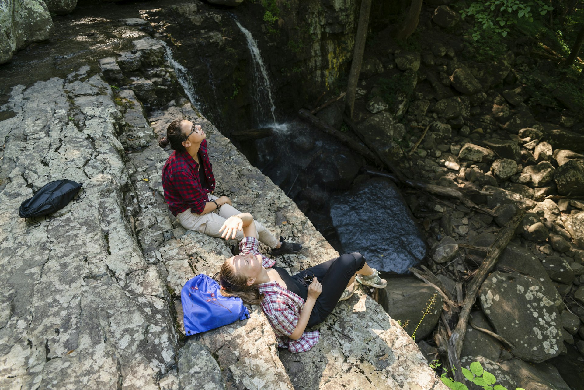 Two teenage girls resting at the top of the rock nearby Dinging Rocks waterfall, Upper Black Eddy, Pennsylvania, Poconos, USA