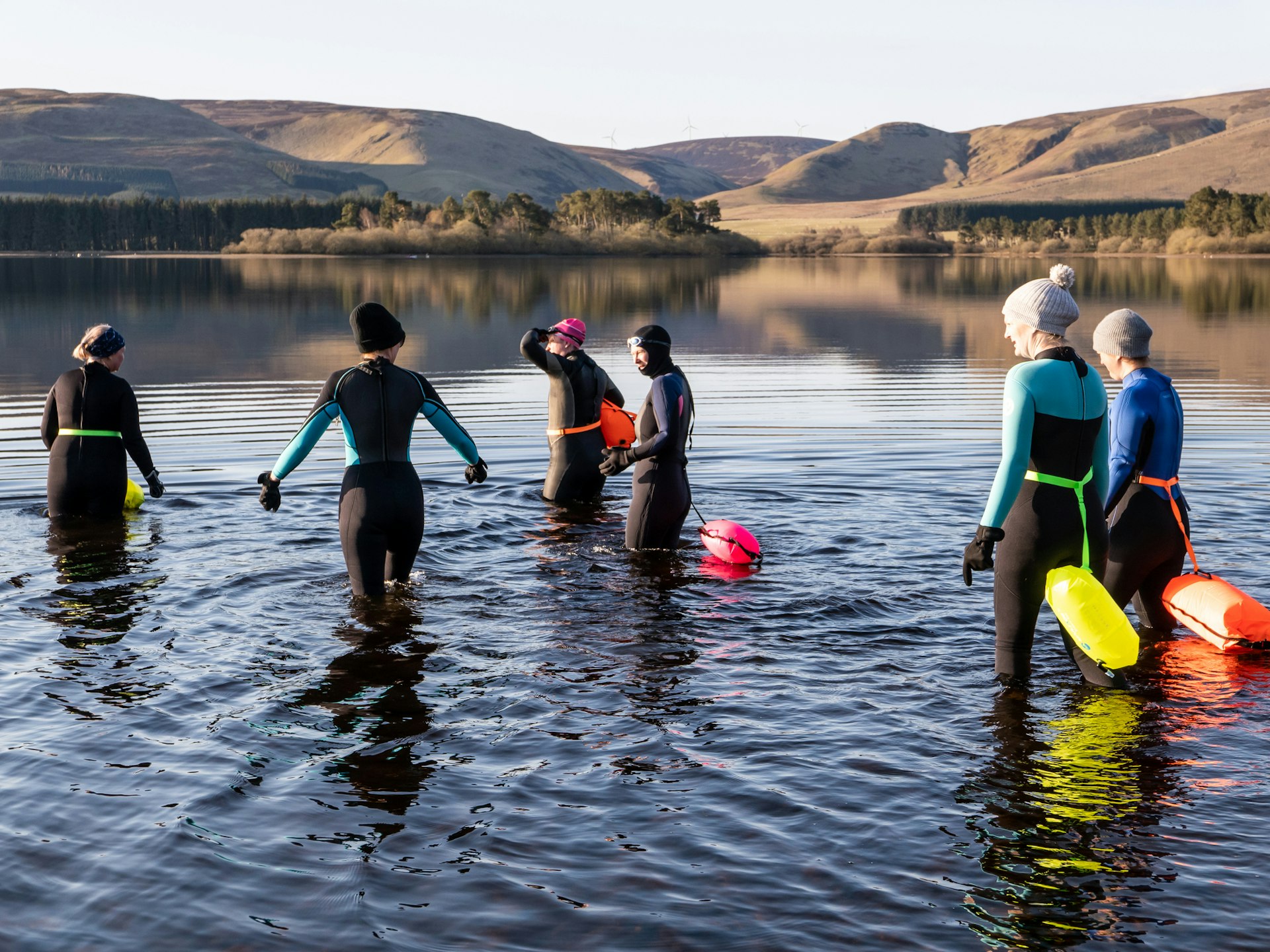 A group in wet suits ready to go to wild swimming in a freshwater reservoir in Scotland
