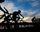 Group of bicyclists rides along the Arkansas River at sunset