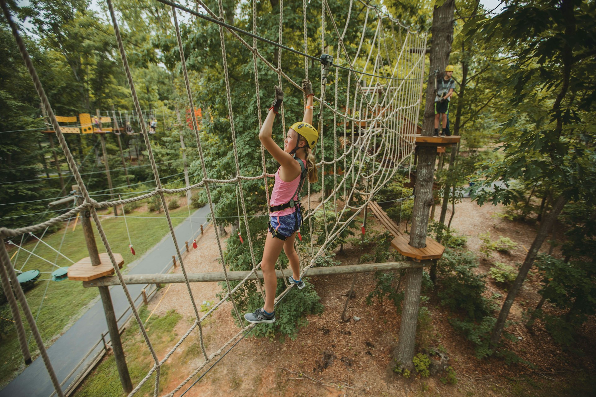 A young girl climbing the ropes of the Greensboro Science Center's treetop adventure