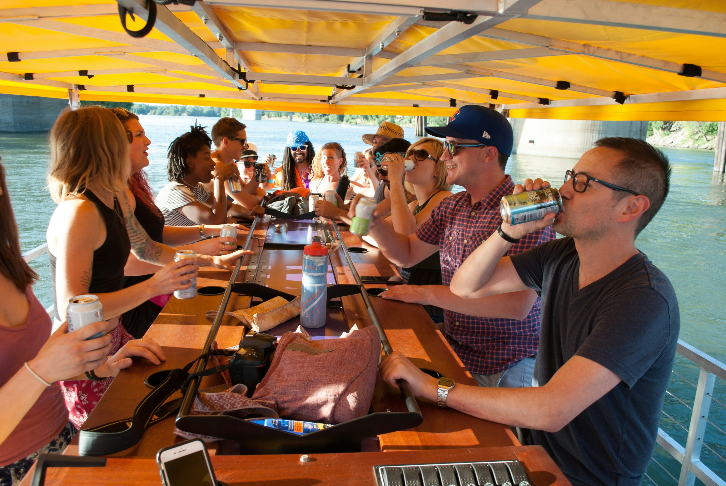 People sitting around a bar on a boat with an awning overhead