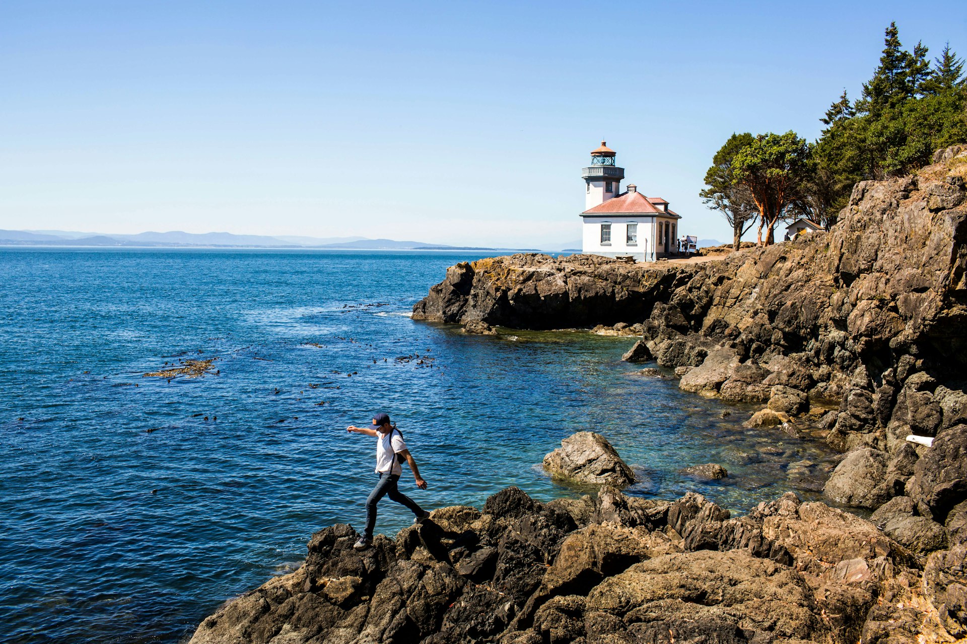 A man walking on rocks near the lighthouse on San Juan Island, Washington, USA