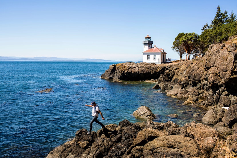 Caucasian man walking on rocks near the lighthouse on San Juan Island, Washington