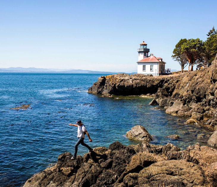 Caucasian man walking on rocks near the lighthouse on San Juan Island, Washington
