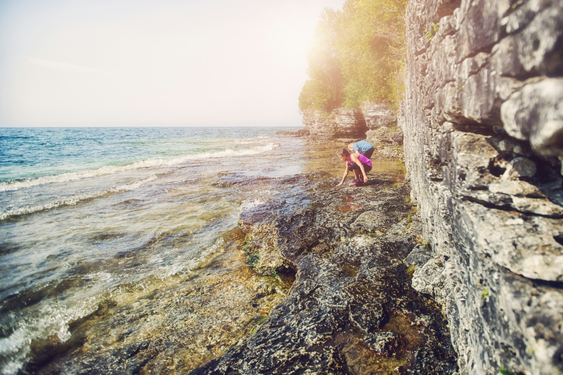 Girl and boy exploring rocks in Cave Point County Park on shores of Lake Michigan