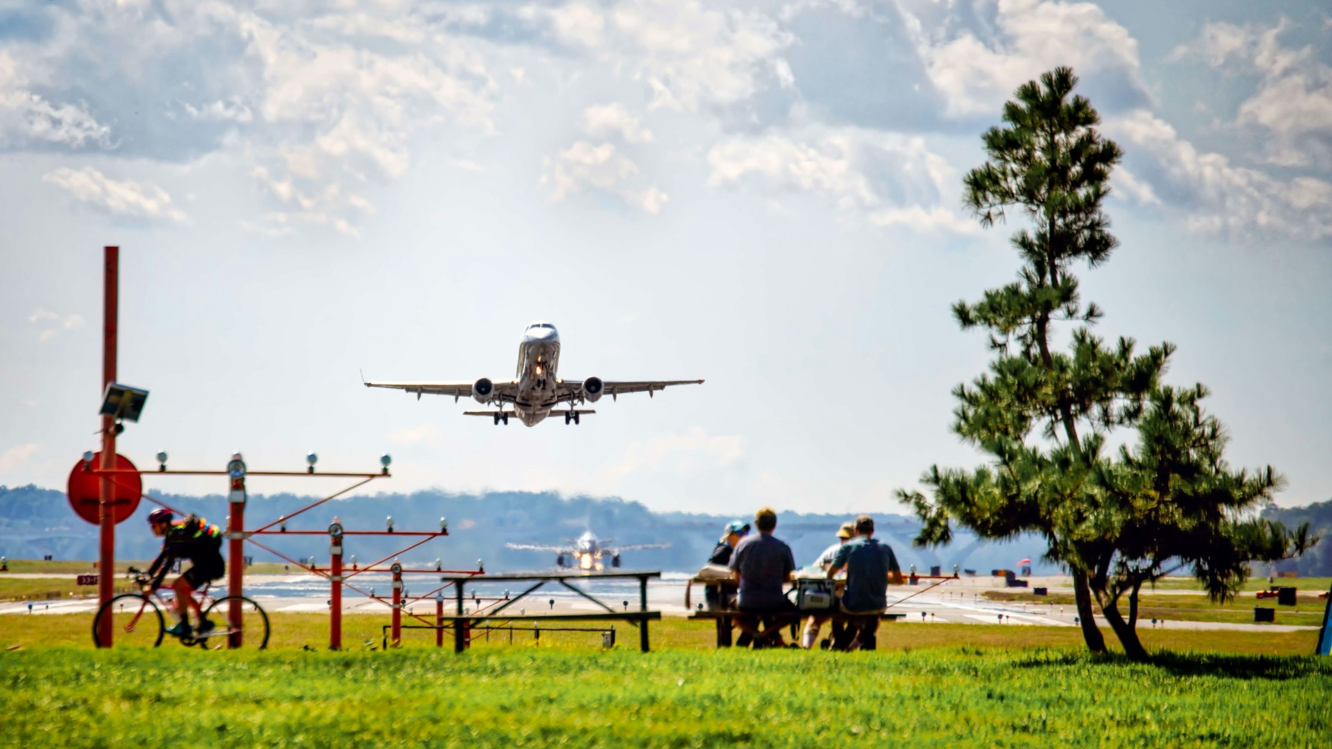 Picnic goers at Gravelly Point Park having their lunch near Reagan National Airport as a plane flies overhead