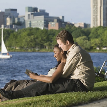 Disabled man reading with his partner by the water in Boston