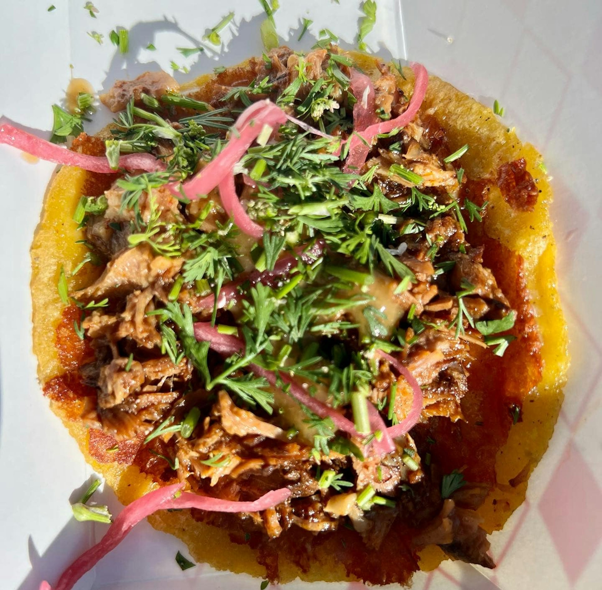 An overhead shot of the Goat Mafia's birria taco with cilantro and pickled onions 