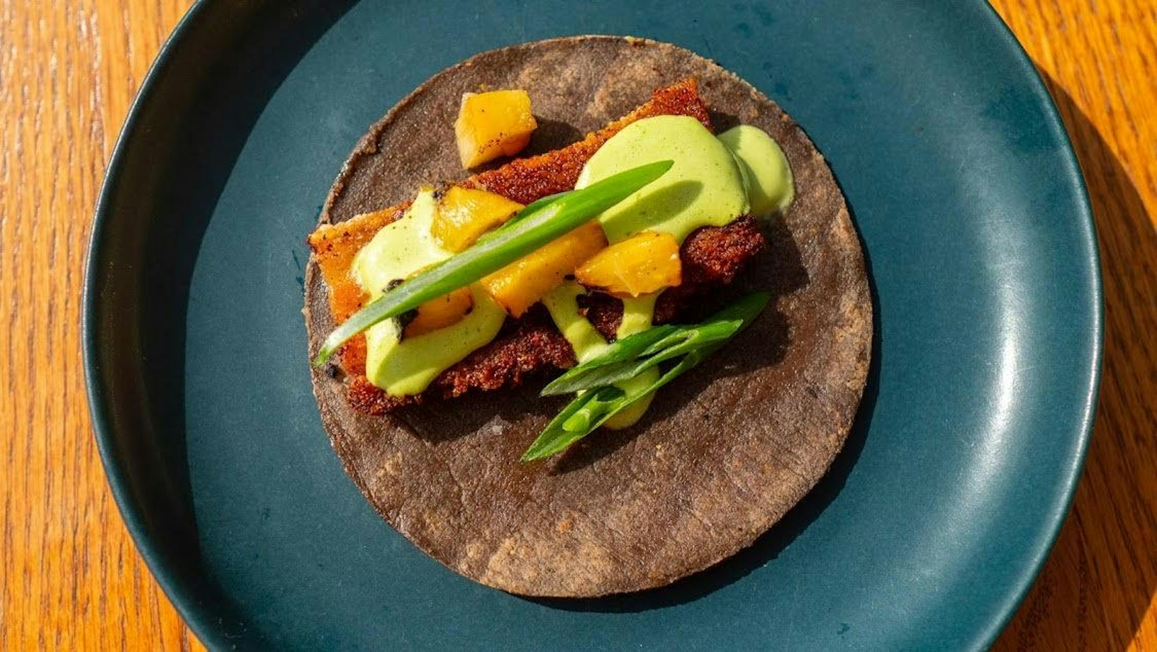 A fancy taco with pork belly and various sauces on a blue-corn tortilla from Nueva in LA