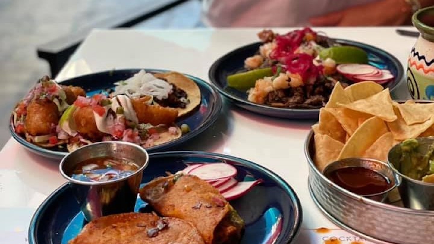 A table with several plates of tacos, chips, and salsa in Los Angeles