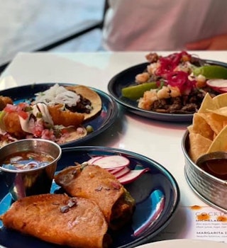 A table with several plates of tacos, chips, and salsa in Los Angeles