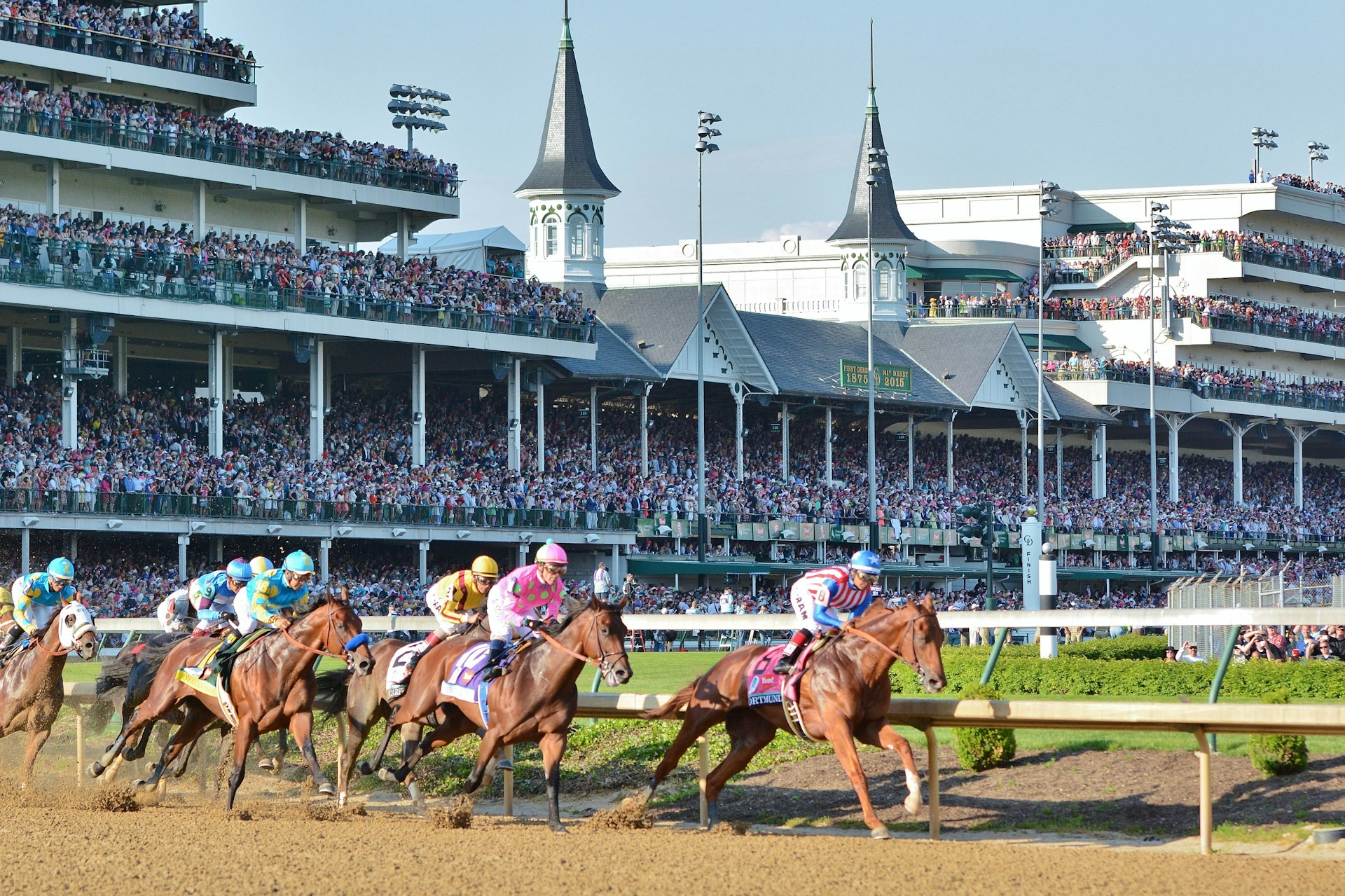 Horses and jockeys taking the first turn at Churchill Downs in Louisville, Kentucky