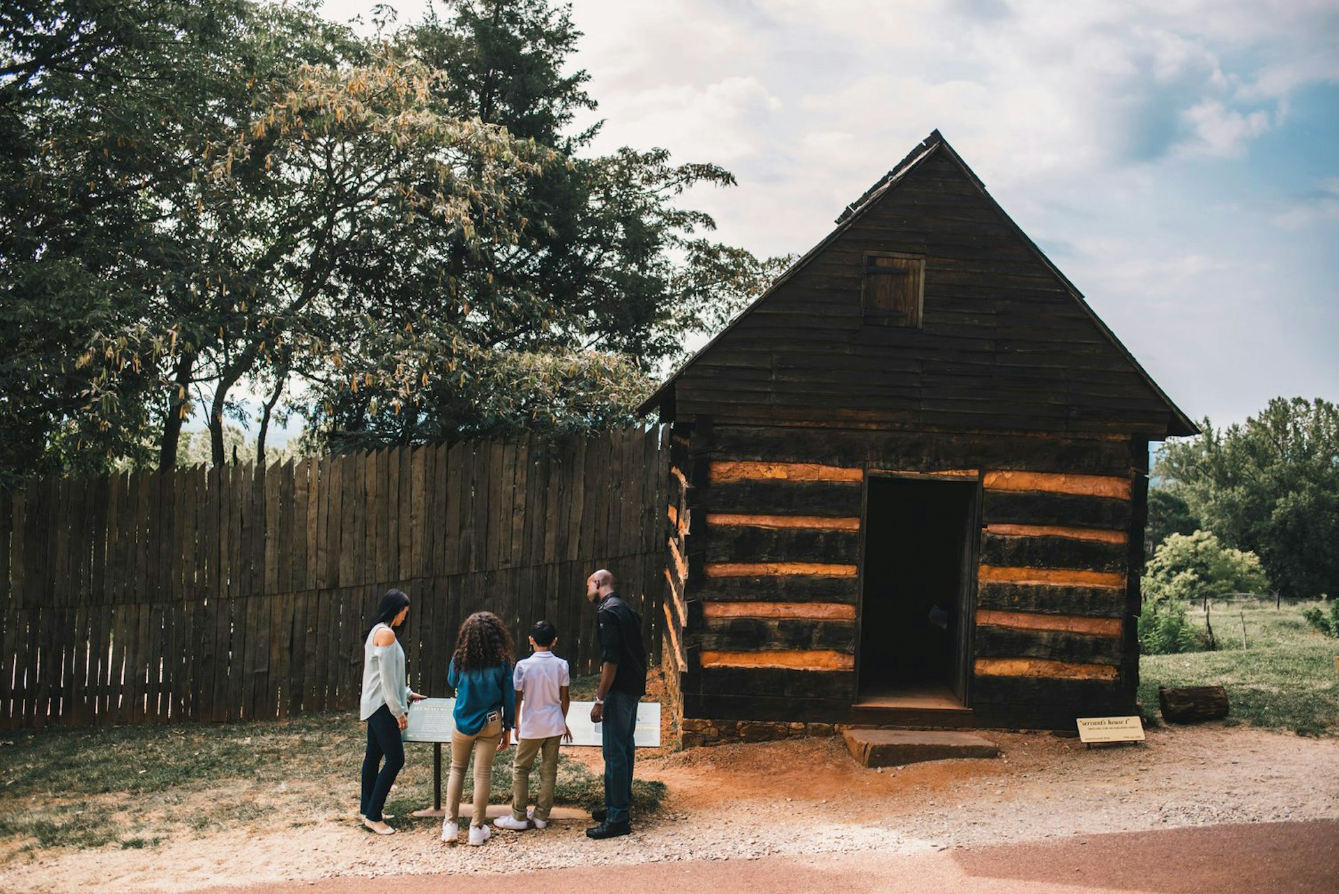 A family looks at a plaque in front of a wooden building at Monticello
