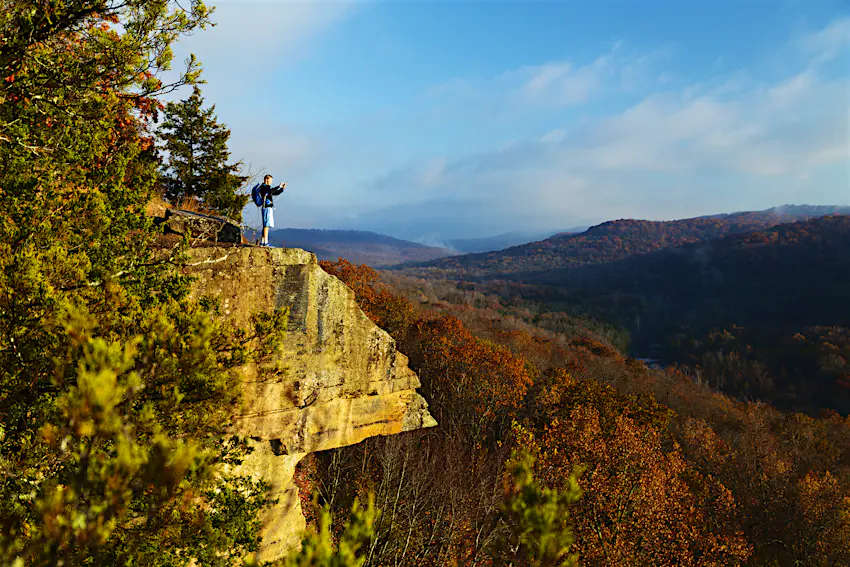Devil's Den State Park, Arkansas A solo hiker stands on a rocky outcrop taking a photo of the landscape in Devil's Den State Park, Arkansas