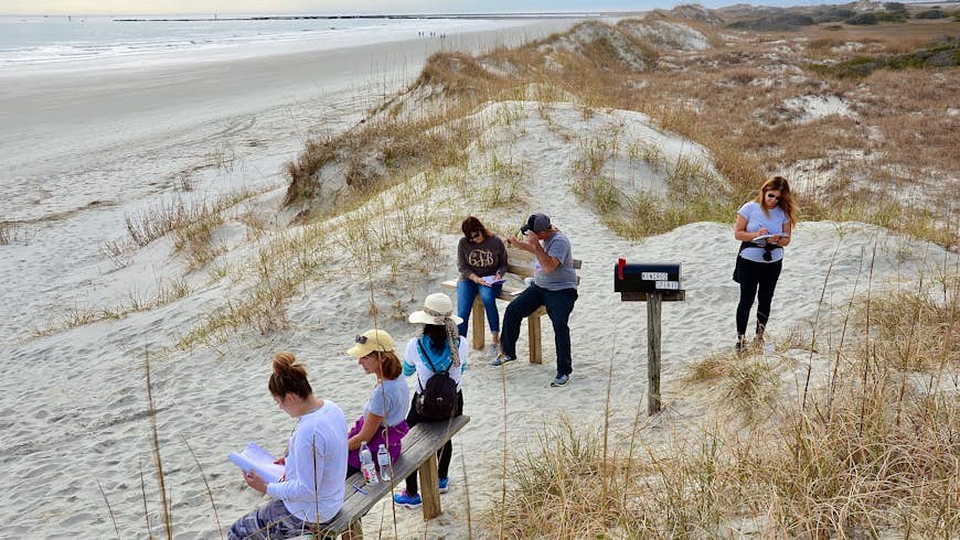 Group of people gathering around Kindred Spirit Mailbox, a unique landmark on the Sunset Beach, to write down their stories or secrets as spiritual release