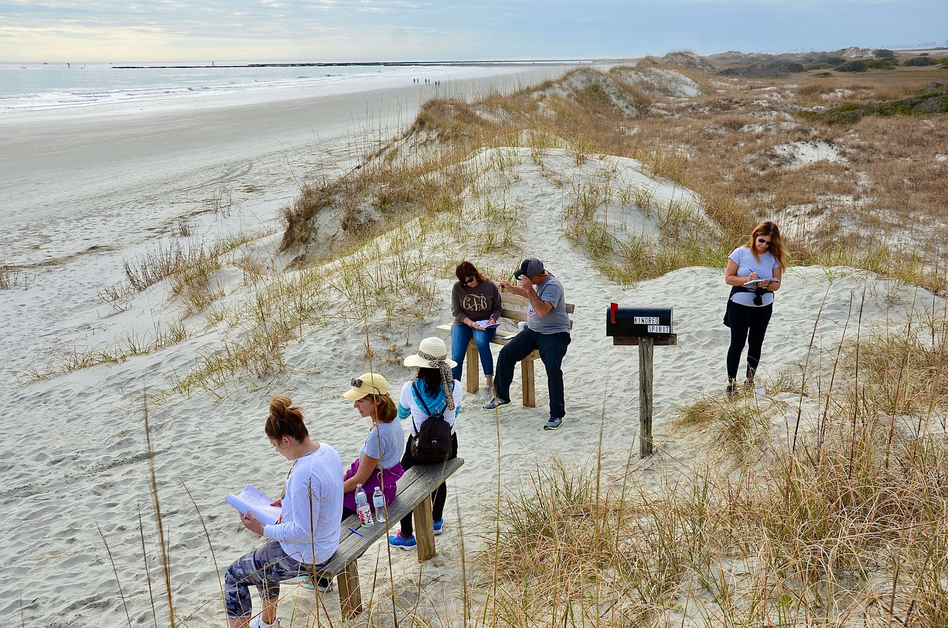 Group of people gathering around Kindred Spirit Mailbox, a unique landmark on the Sunset Beach, to write down their stories or secrets as spiritual release