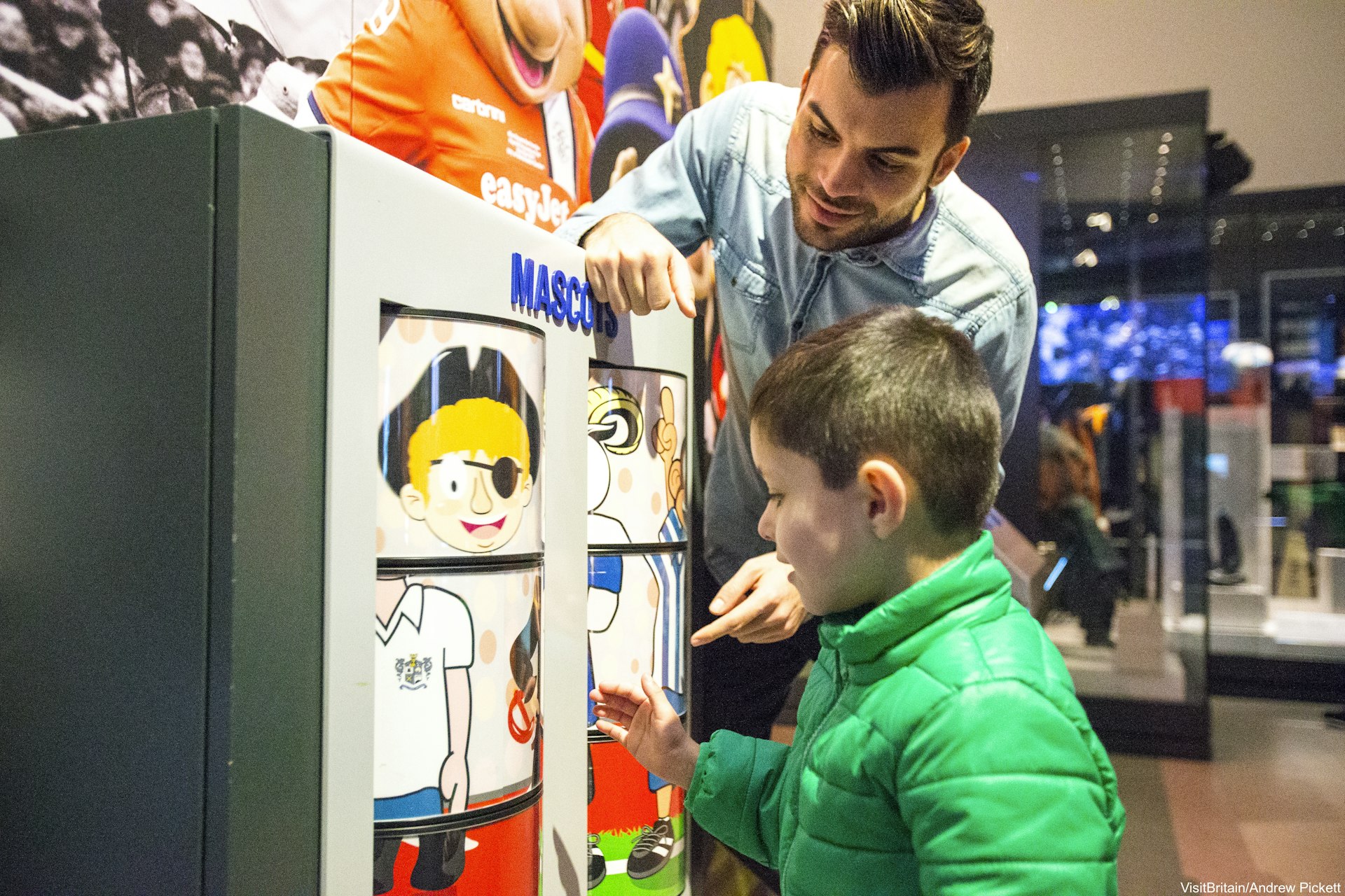 An Arabic family, a father and son visiting the The National Football Museum - using interactive exhibits about the game of soccer and its history.