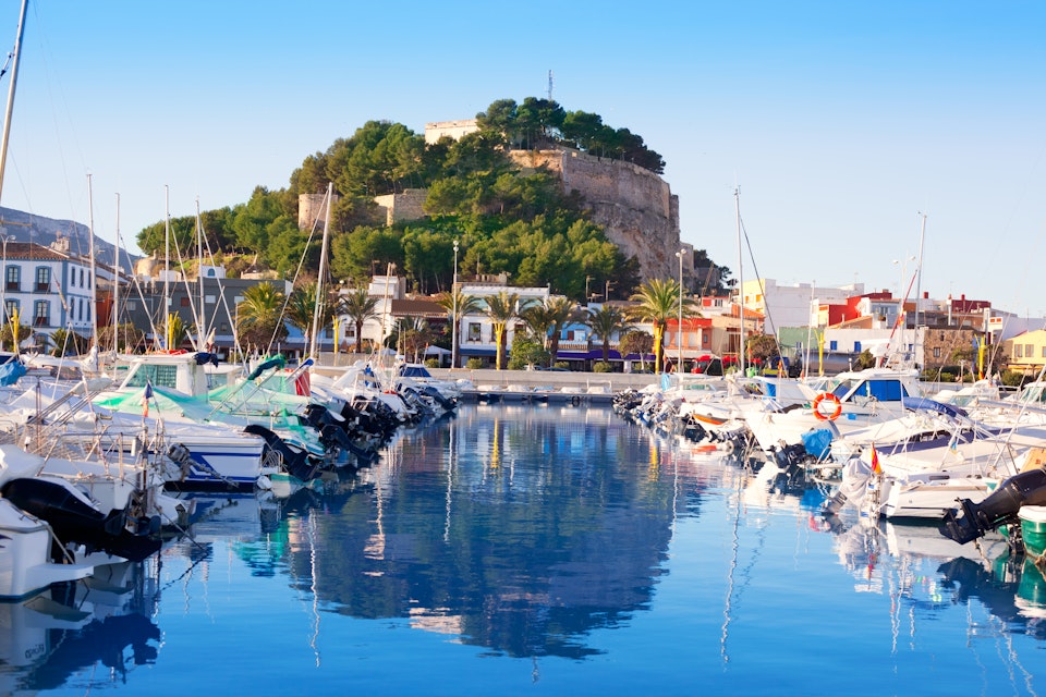 Denia mediterranean port village with castle mountain and blue sea water