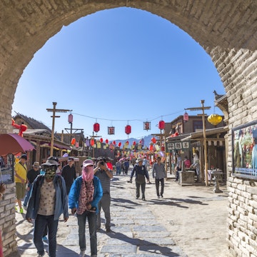 Yinchuan, Ningxia, China - June 11, 2015: Entrance of an ancient castle of Qing Dynasty near Yinchuna of Ningxia, China. It is a national AAAA level scenic area. It is thought to have been built during Qing dynasty and used to guard the Yinchuan city. Some tourists are walk through the entrance and wearing mask to prevent sands and dirt in the air.
