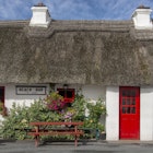 Facade of an old cottage with a thatched roof after a Facade of an old cottage with a thatched roof after a rainshower on a sunny day.Facade of an old cottage with a thatched roof after a rainshower on a sunny day..