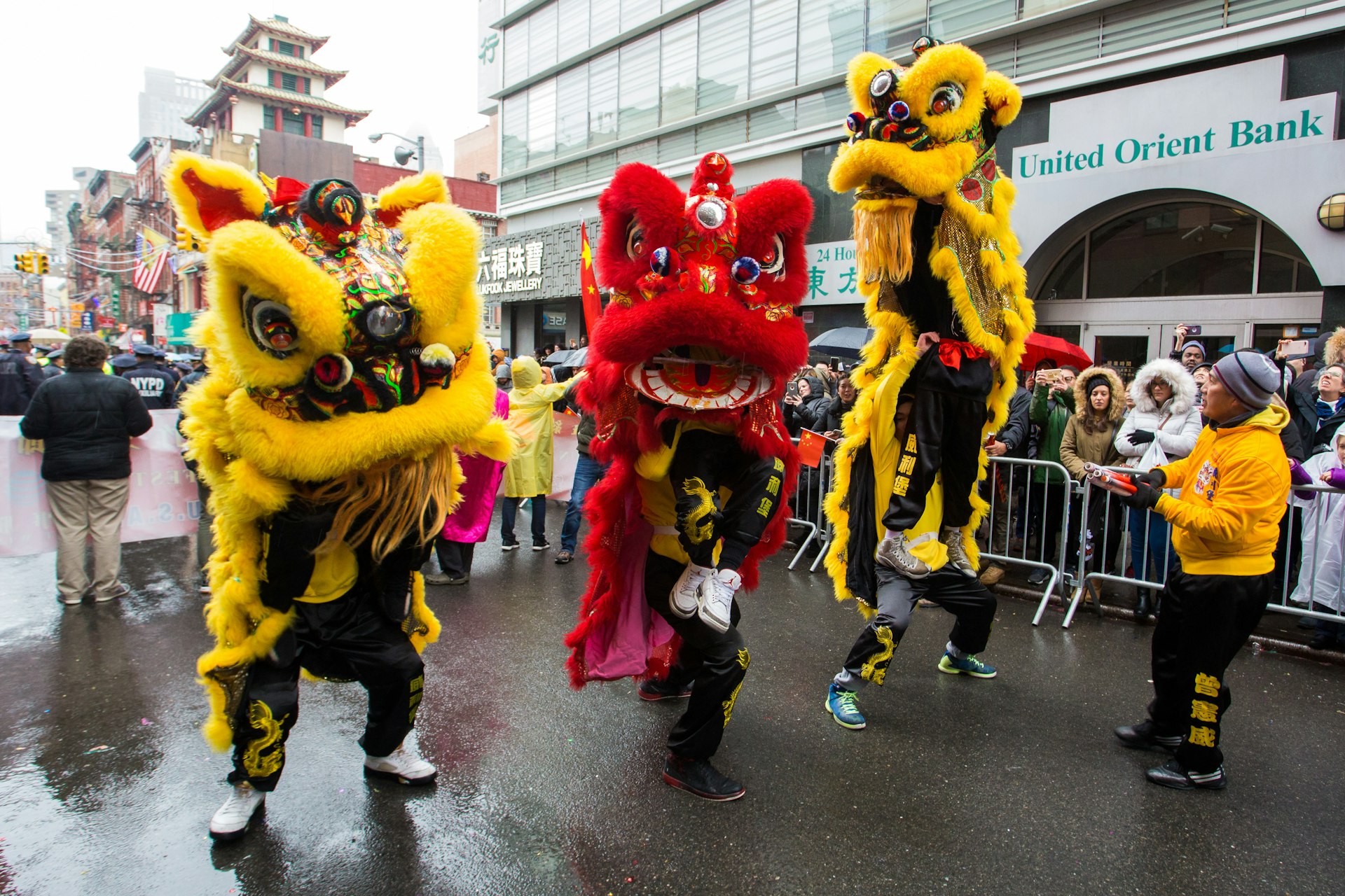 Dancers in brightly colored traditional costumes perform in the rain during a Chinese Lunar New Year parade in Chinatown, New York City, New York, USA