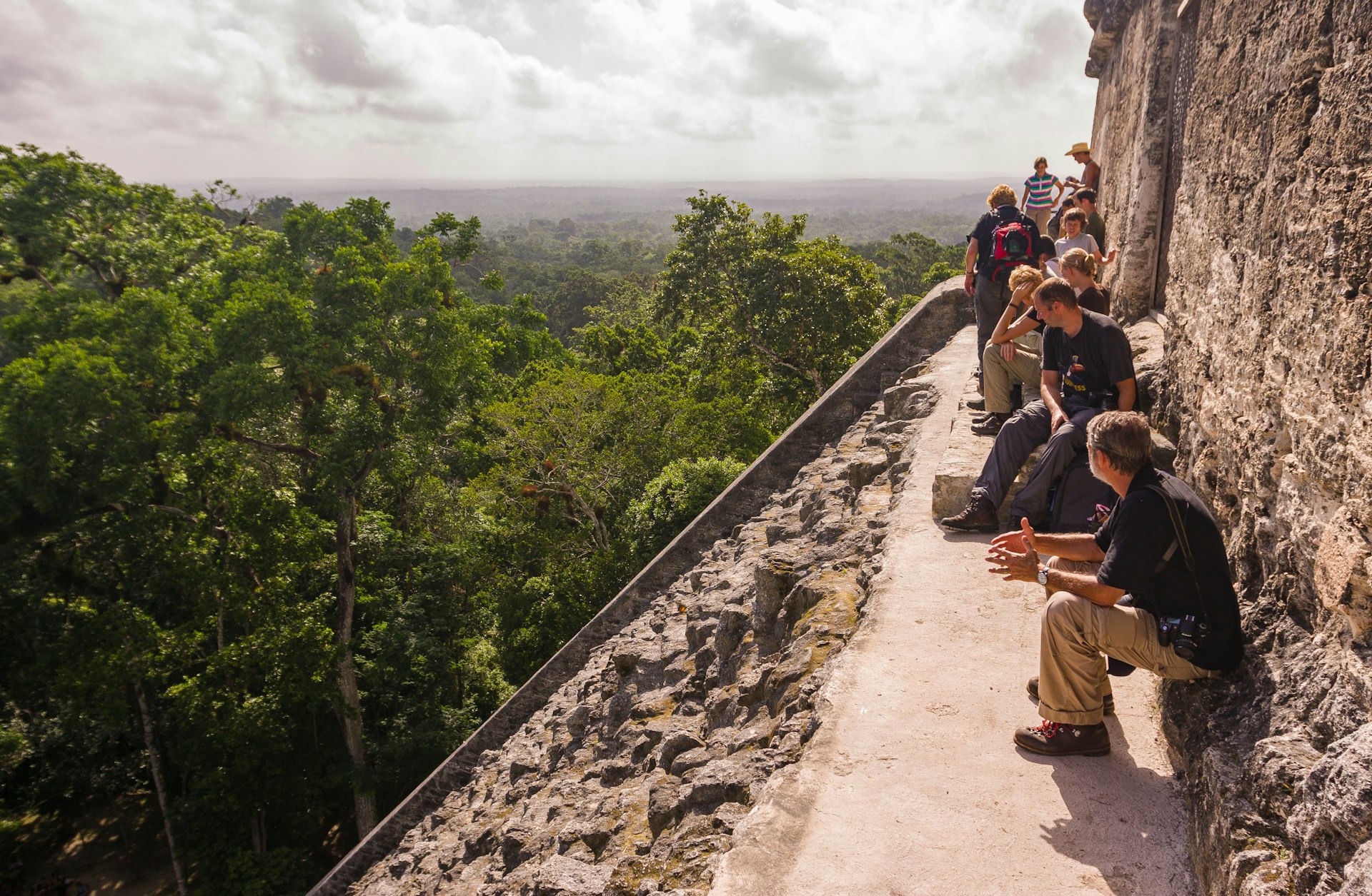 ,Tourists on top of Temple V, at the Mayan ruins of Tikal, located in El Petén department, Tikal National Park, Guatemala