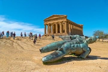 April 2, 2018: The Icarus statue, with tourists visiting the Temple of Concordia in the background.