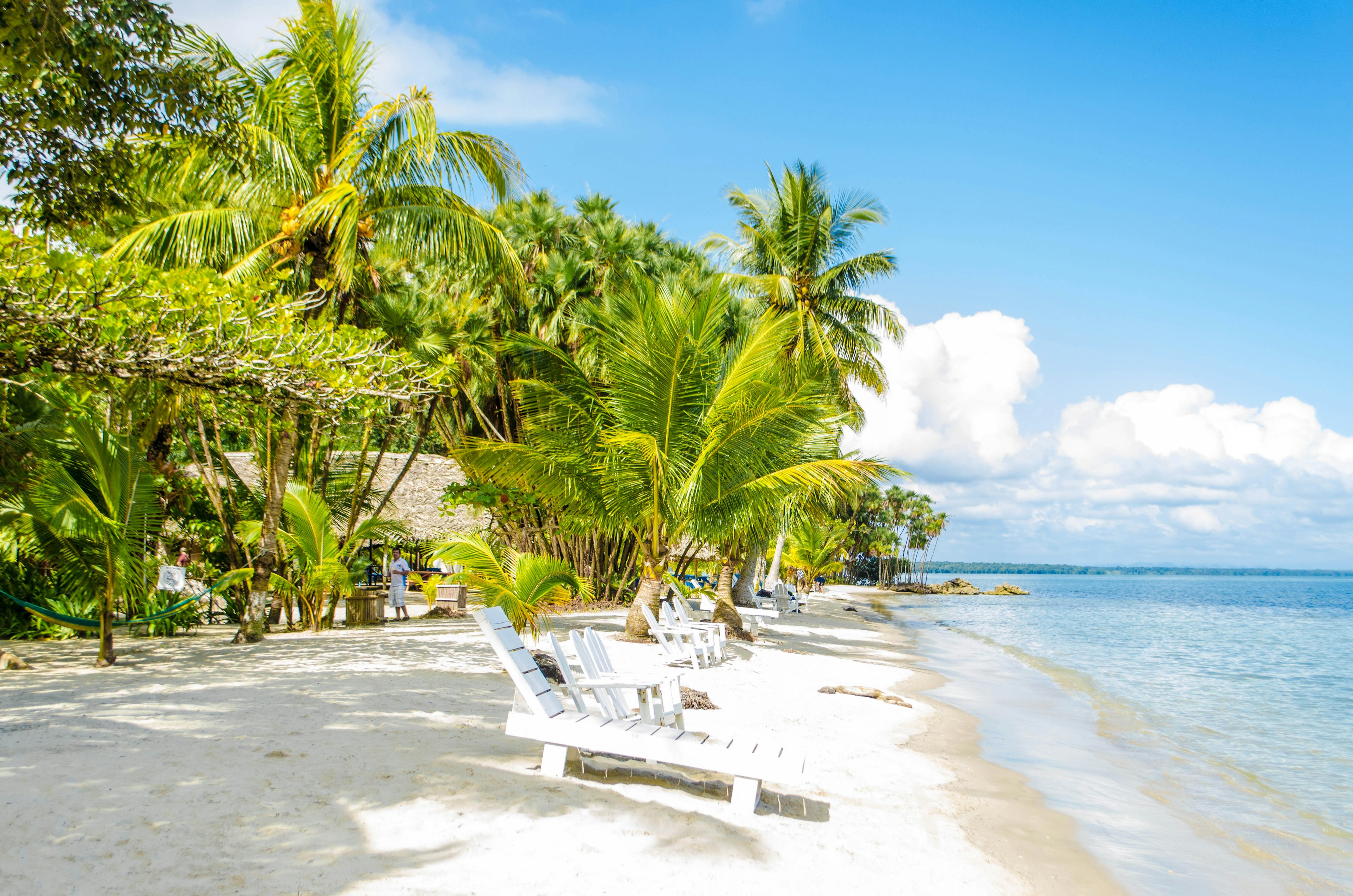 White chairs and palm trees on the beach of Playa Blanca in Guatemala