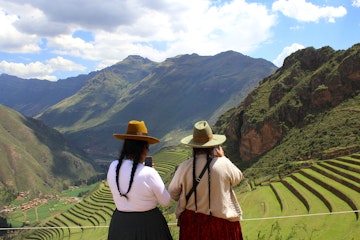 Two Peruvian woman look at their phones at the ancient ruins of Pisac.