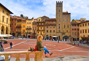April 25, 2019: Woman sitting on a stone handrail at Piazza Grande square in Arezzo.