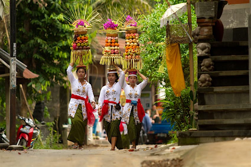 Village women carry offerings of food on their heads in a temple procession near Ubud 